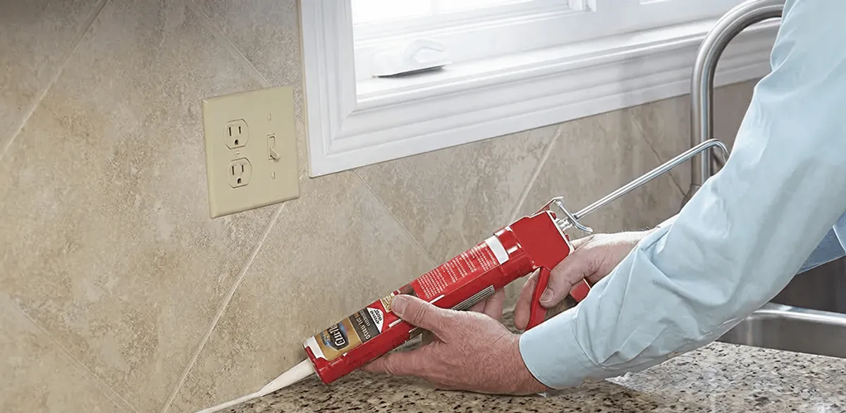 Handyman applying caulk along a kitchen backsplash and countertop seam in Chandler, AZ