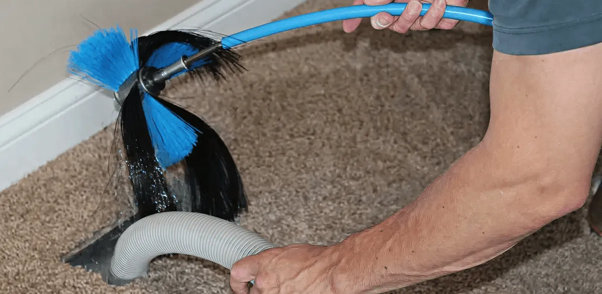 Dryer vent cleaning technician brushing lint from a vent line in Chandler, AZ